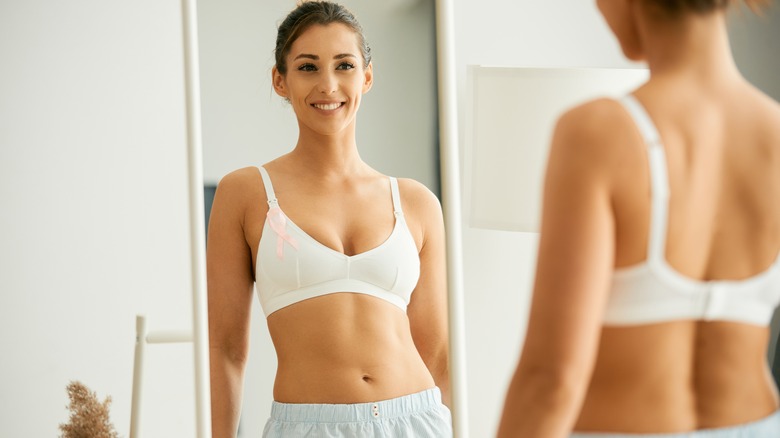 woman looking at her breasts in the mirror