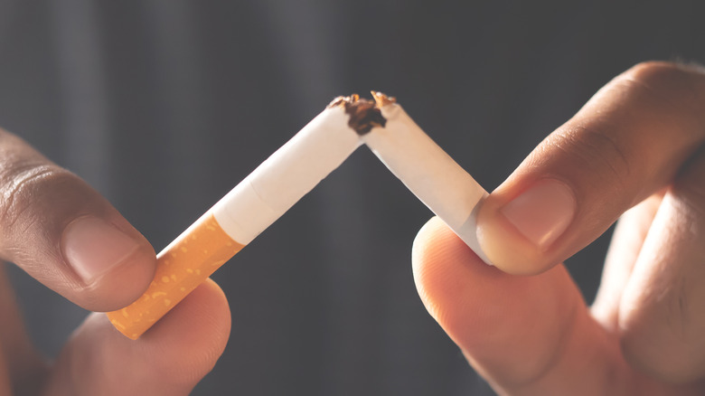 male hands breaking a cigarette in half