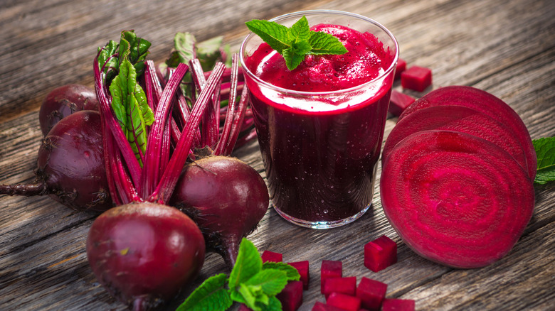 A glass of beetroot juice surrounded by whole, cubed, and halved beets