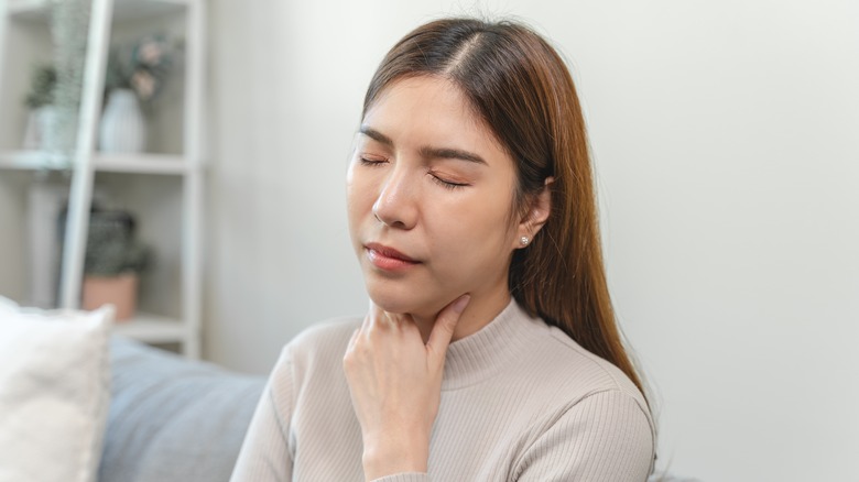 woman holding her sore throat