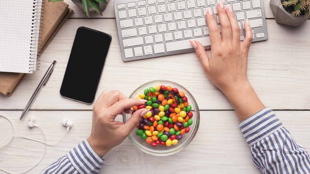 Woman eating candy while typing on computer