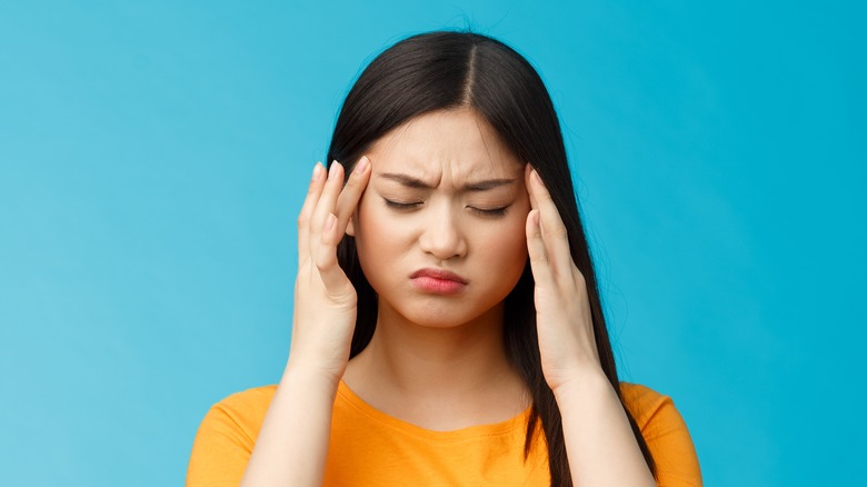 girl with headache holding temples