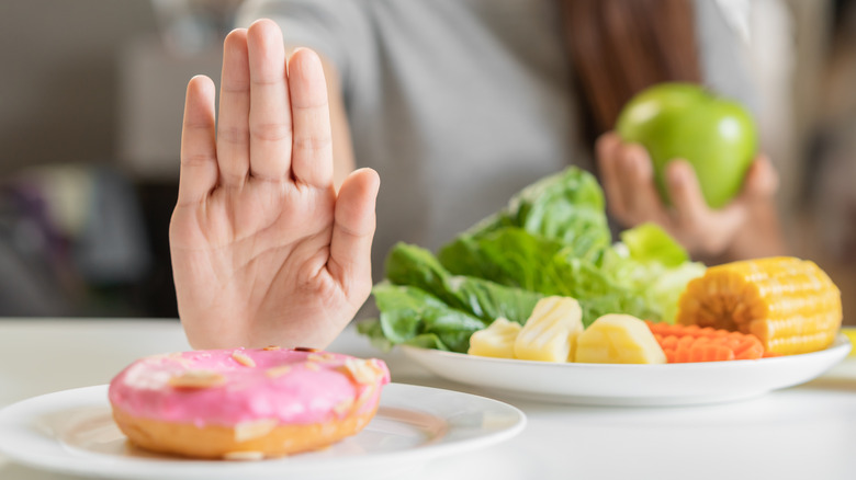 person refusing donut and eating salad