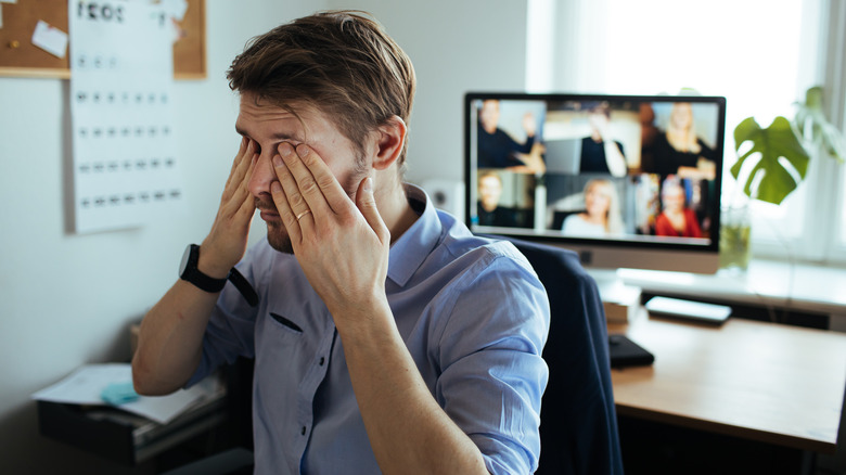 tired man rubbing eyes at work