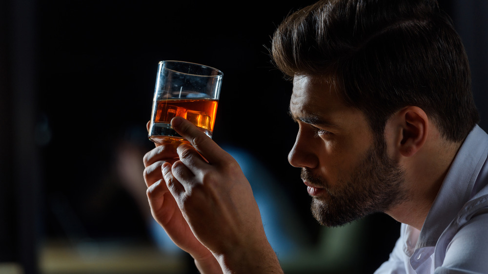 man looking at whiskey glass