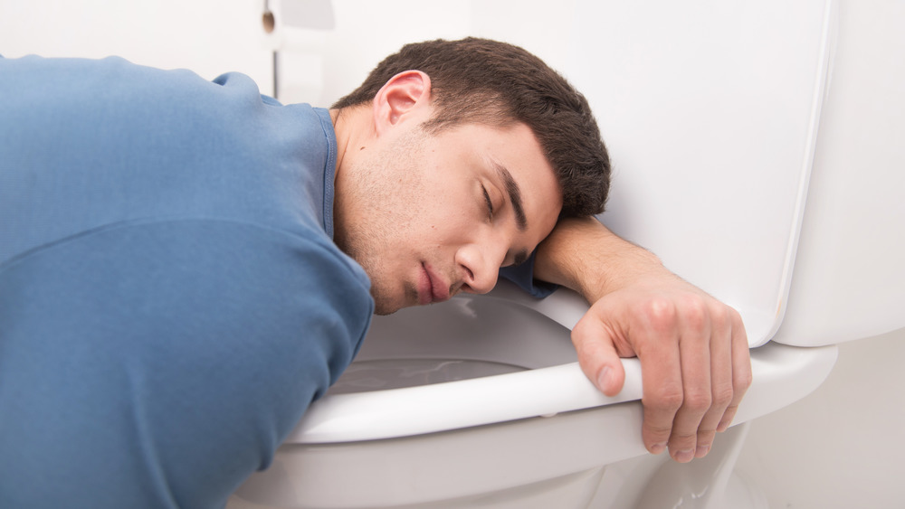 man resting head on toilet
