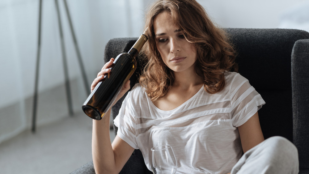 woman holding wine bottle against head