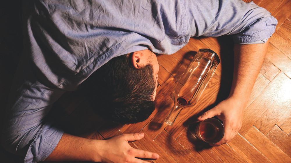 man lying on floor with alcohol