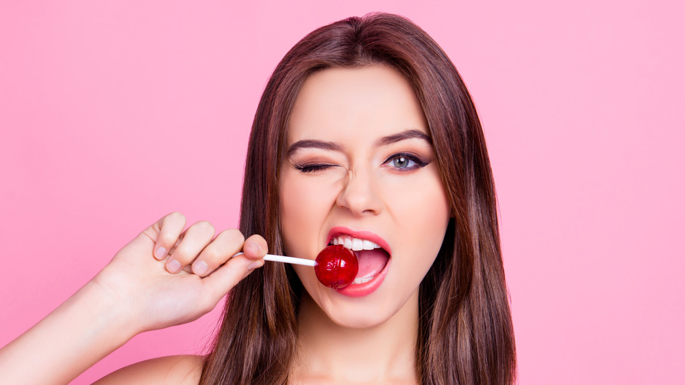 woman biting lollipop