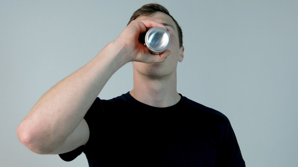 man drinking can of soda