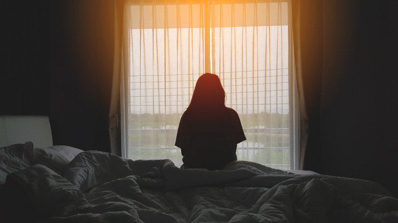 woman resting on bed looking out window