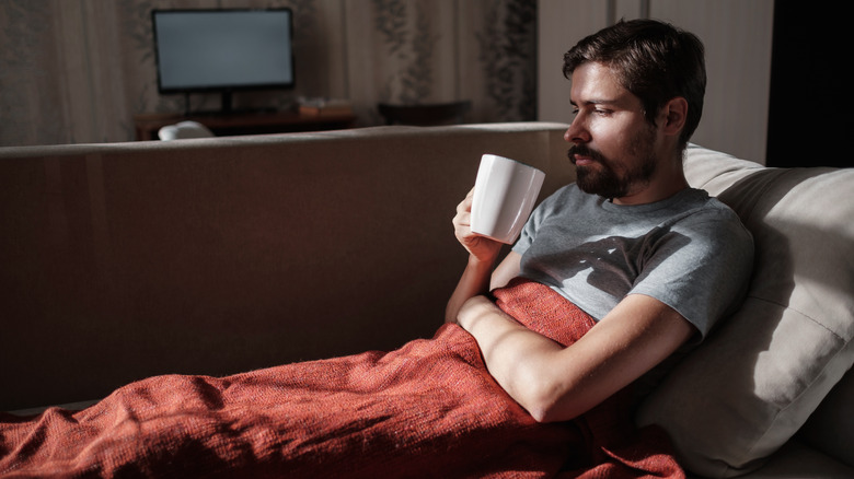 young man not feeling well lying on his couch 