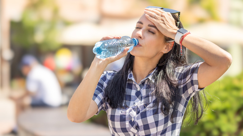 woman outside drinking water for headache