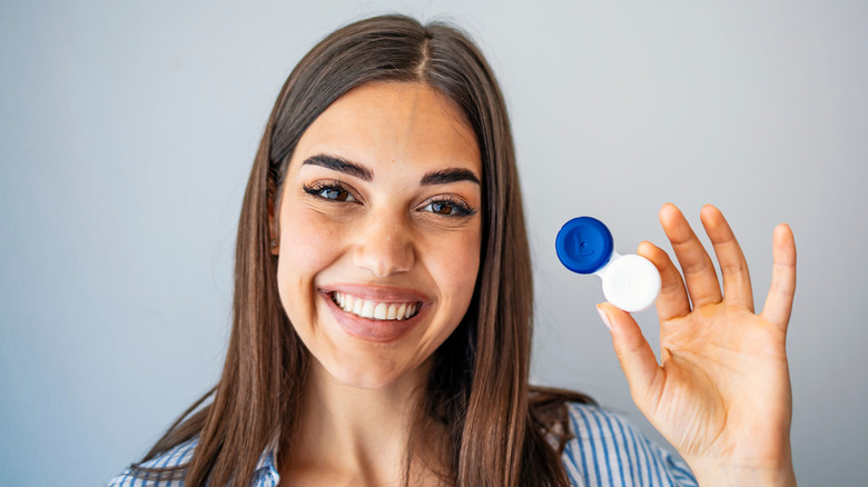 A smiling woman holding up a contact case