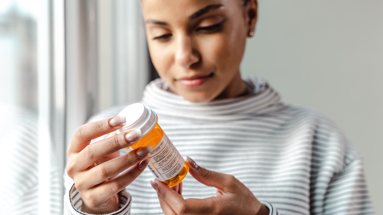 woman looking at her prescription bottle