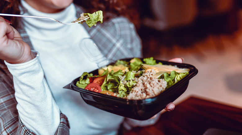 a woman eating a salad with canned tuna