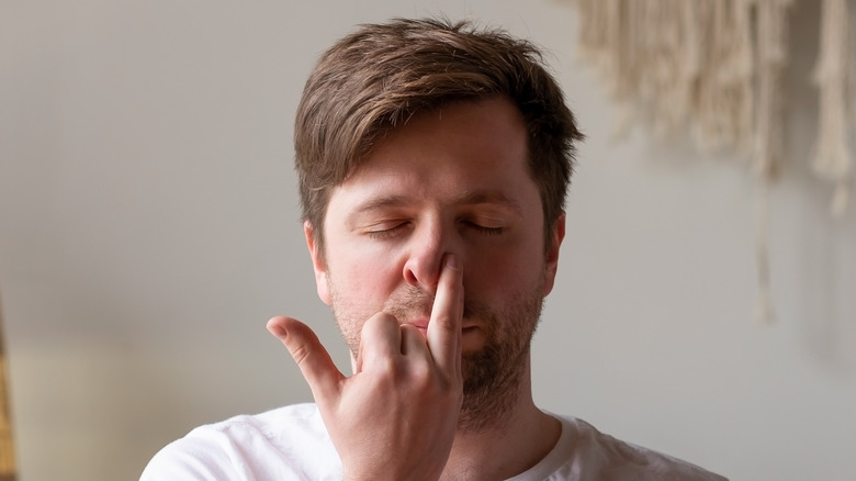 Man with eyes closed engaged in right nostril breathing yoga exercise