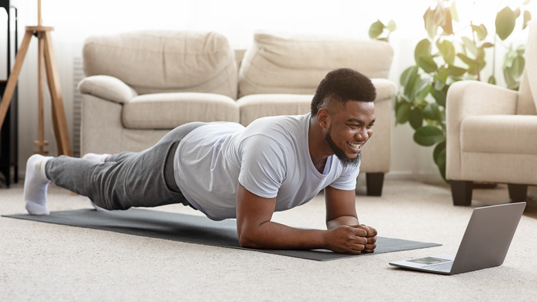 man doing planks in front of laptop