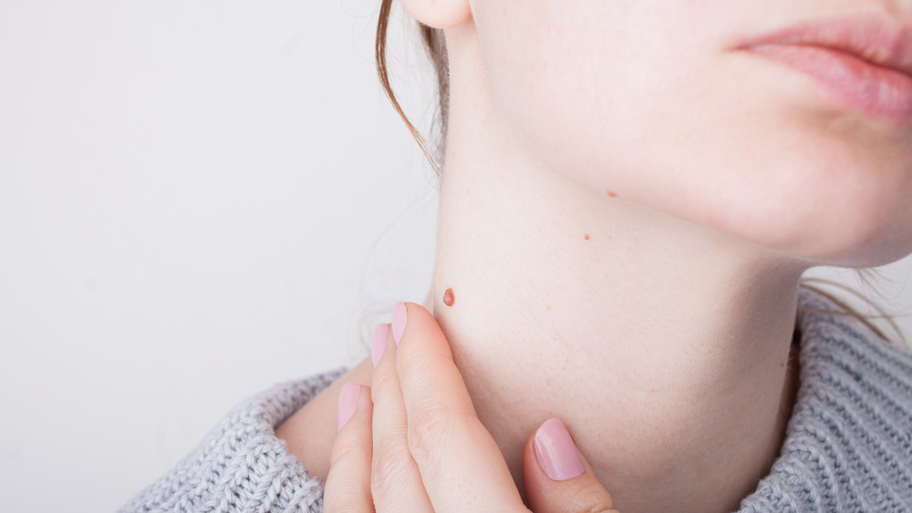 woman looks at mole on neck