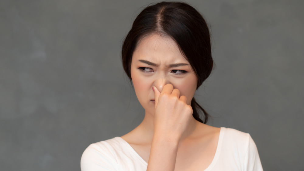 woman holding nose to indicate foul smell