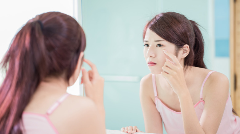 woman looking at eye in the mirror