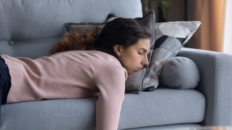 Woman in pink sweater lying on couch with eyes closed