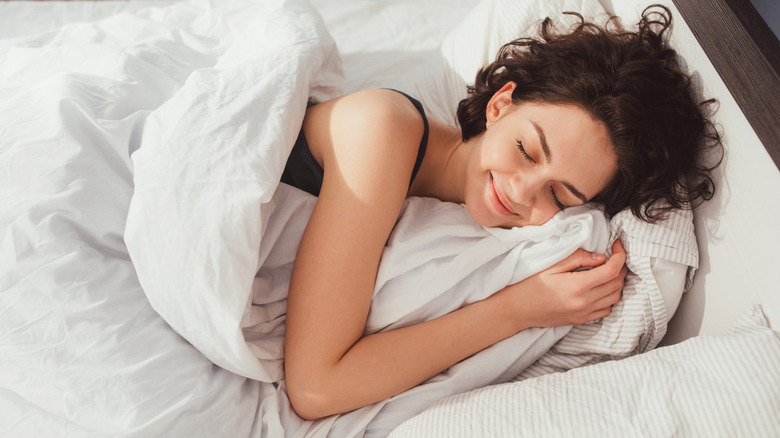 Woman sleeping in bed covered with blanket
