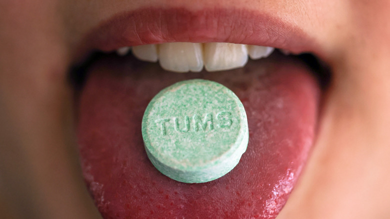 Close up of mouth with a green Tums pill sitting on person's tongue
