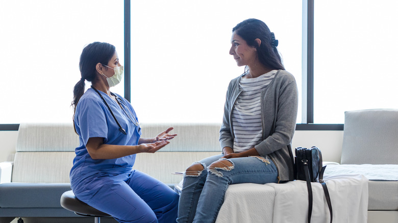 doctor advising woman sitting on bed