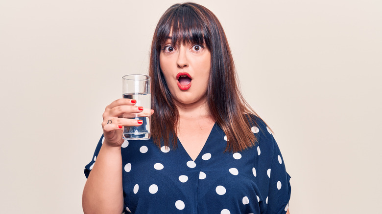 surprised woman holding up glass of water