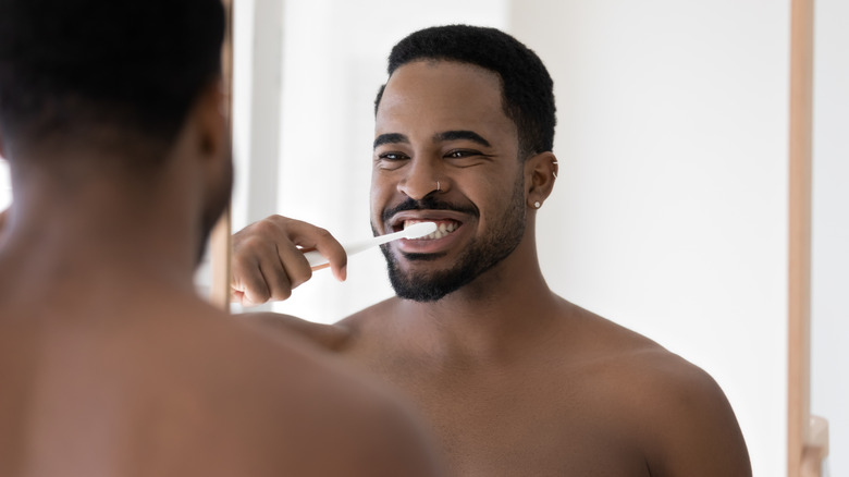 man mirror brushing teeth