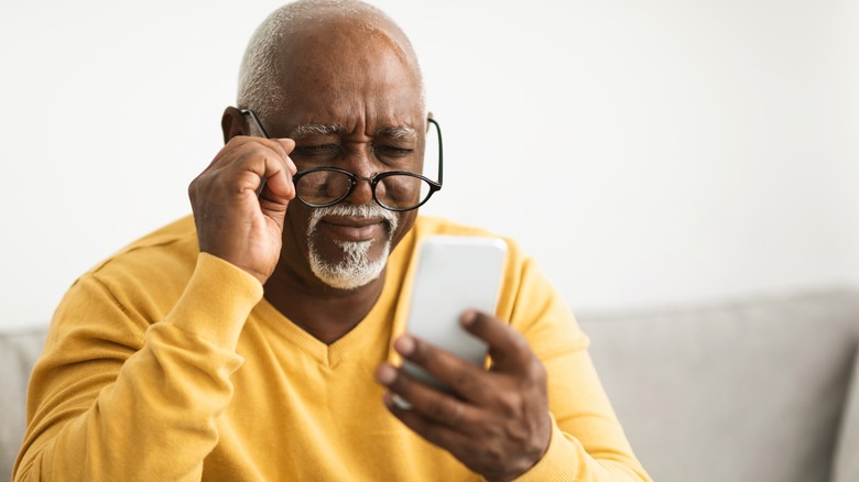 older man struggling to see his iPhone