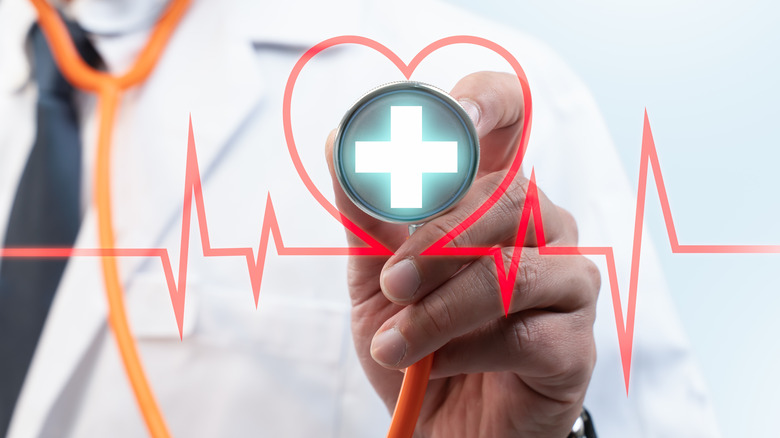 doctor with stethoscope touching heart rate symbol