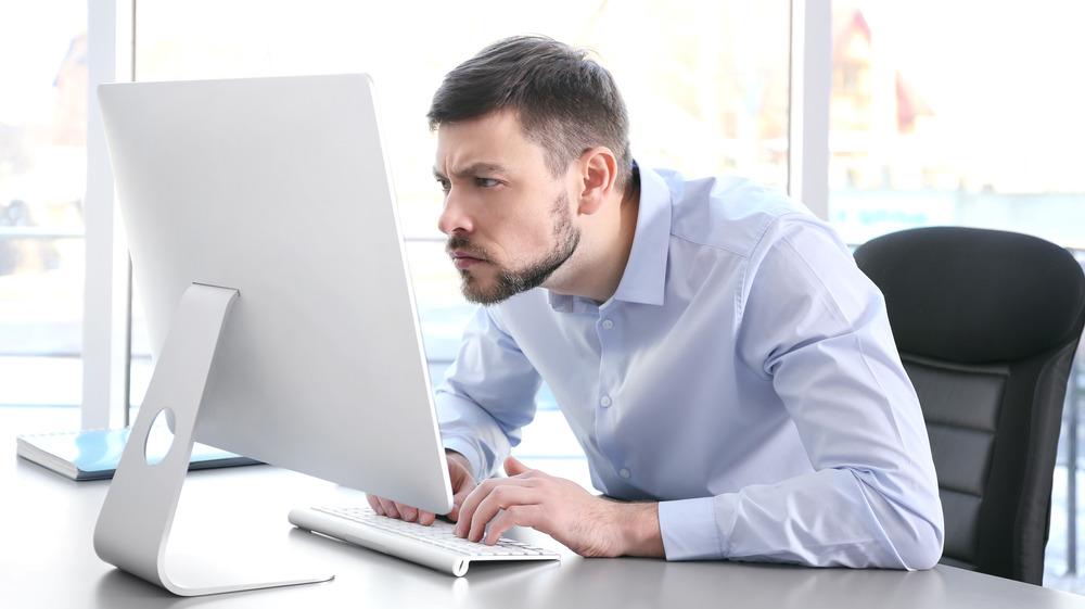man slouching, working on computer
