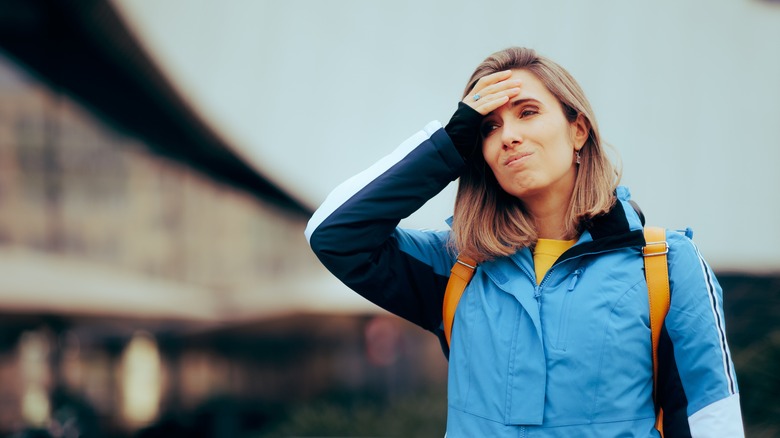 woman holding her hand on her head, feeling disoriented