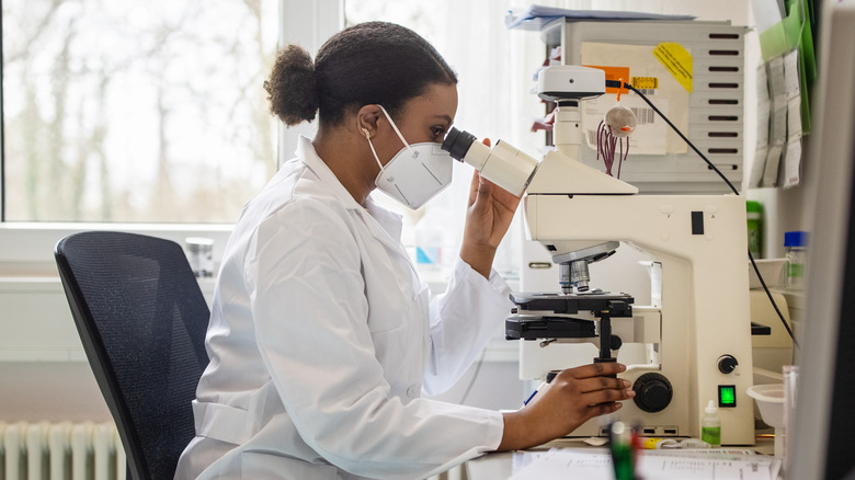 medical researcher looking through microscope