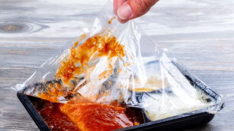 person peeling plastic off frozen meal