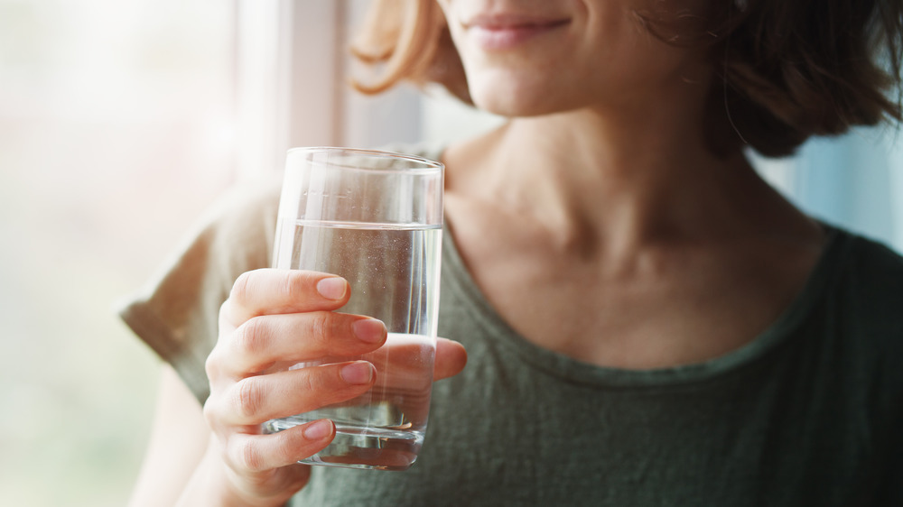 Woman drinking water by window