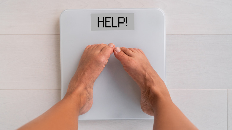 top view of a person on the scale with the word "help" 