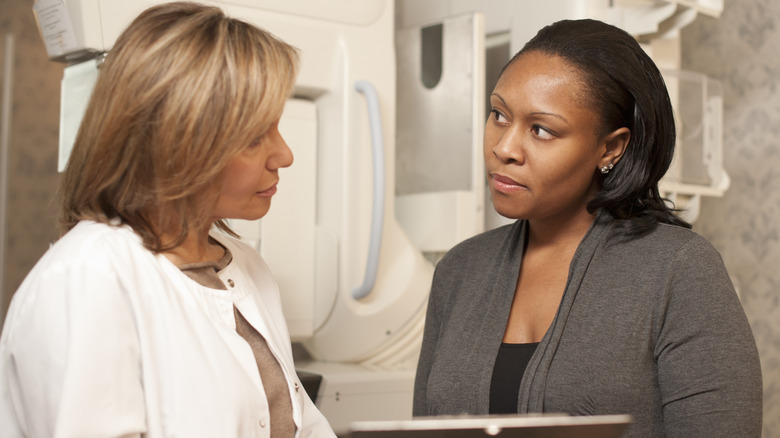 Woman talking to her doctor in front of mammogram machine