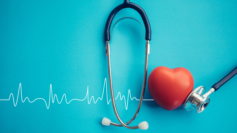 An EKG reading behind a stethoscope and a heart against a blue background