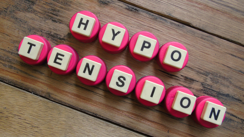 The word "hypotension" divided in a half and spelled out with white blocks on pink circles on two separate lines