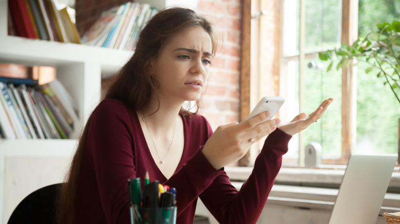 Irritated woman holding phone