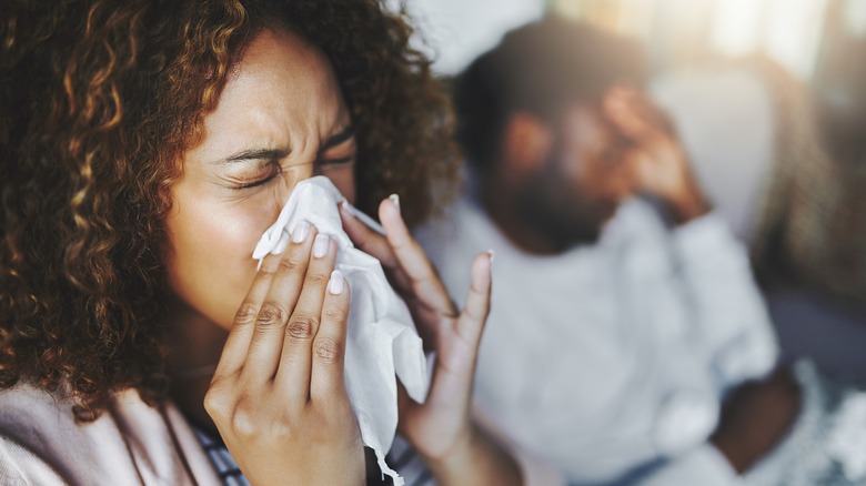 sick woman blowing her nose