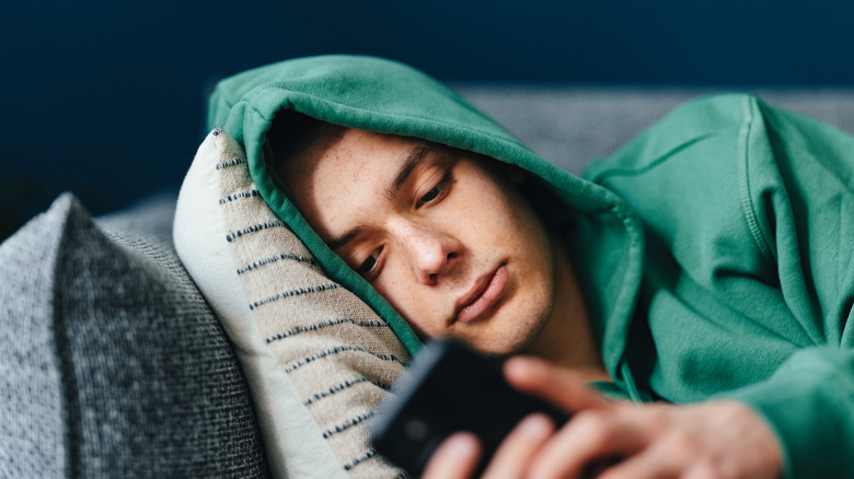 Sad young man texting on couch