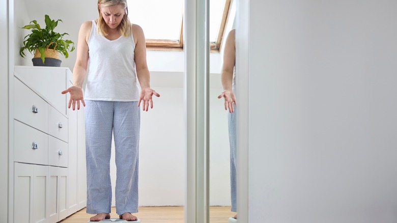 Woman standing on scale looking concerned