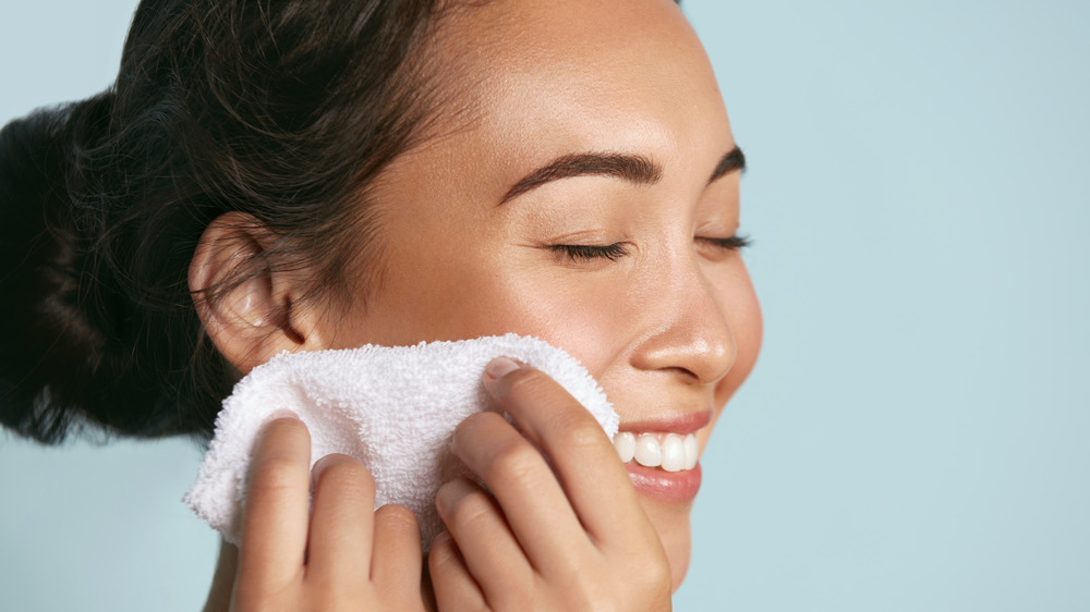 woman cleaning face with washcloth
