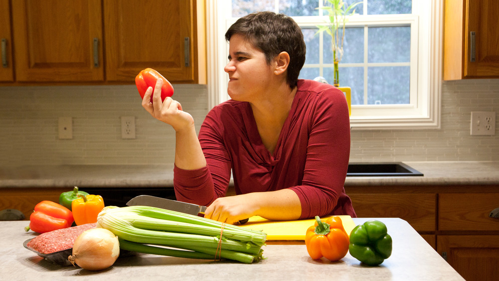 Woman frowning at red bell pepper