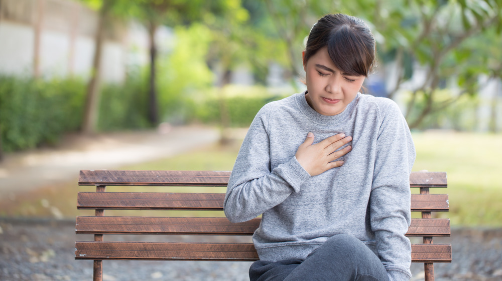 Woman with heartburn on park bench