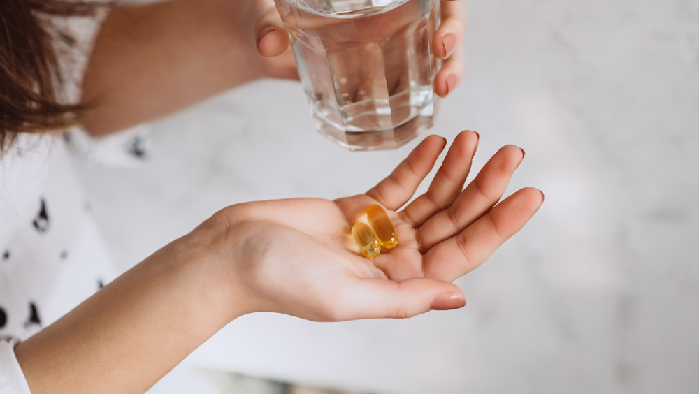 woman holding two vitamin E capsules